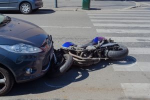 Motorcycle laying in front of car