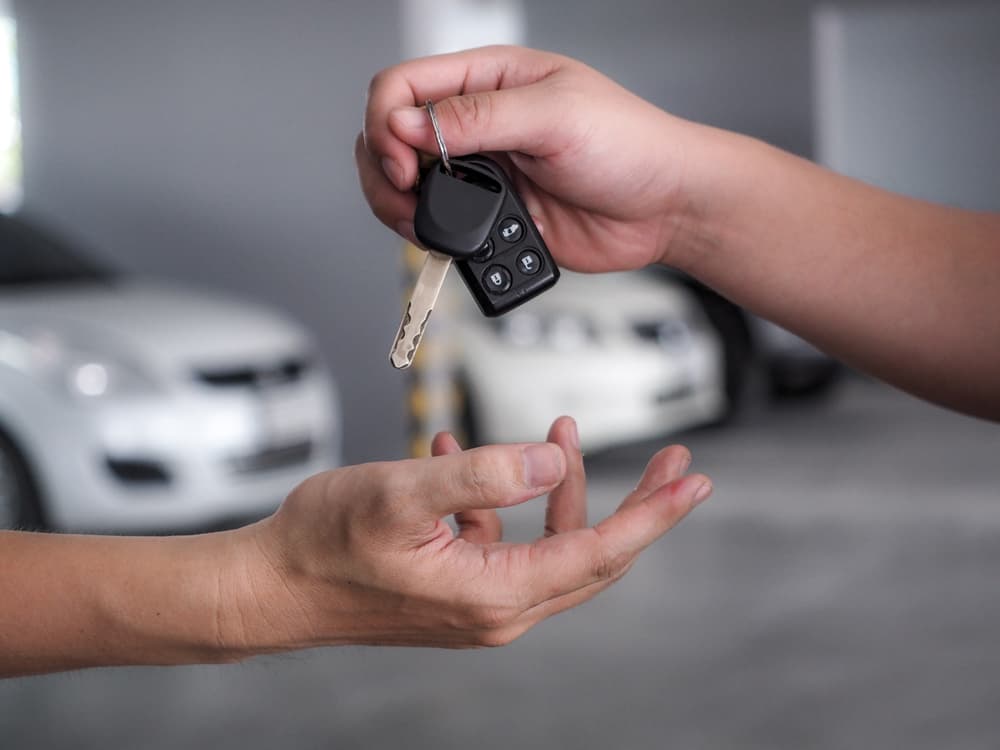 Car Owner handing over car key to another person