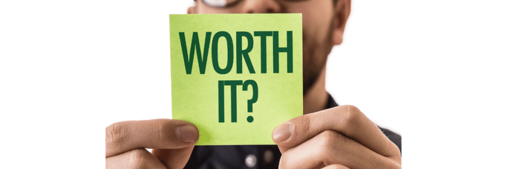 A man holding up a sticky note that says 'Worth It?'