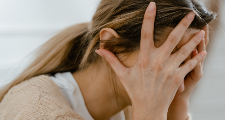 A woman conceals her face with her hands, expressing emotions of distress or contemplation in a thoughtful pose.