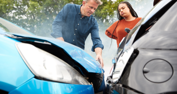 A man and woman examine a damaged car, expressing concern over the vehicle's condition and potential repairs needed.